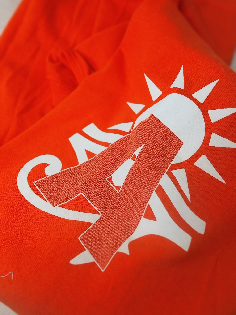 Bright Orange Graphic Tee with White Sun & Letter A